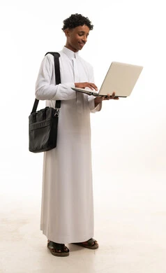 شاب سعودي بالثوب الأبيض يحمل كمبيوتر محمول بخلفية بيضاء