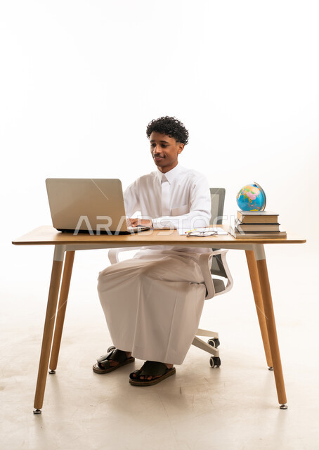 شاب سعودي بالثوب الأبيض يستخدم الحاسوب المحمول