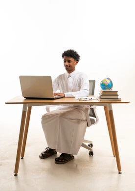 شاب سعودي بالثوب الأبيض يستخدم الحاسوب المحمول