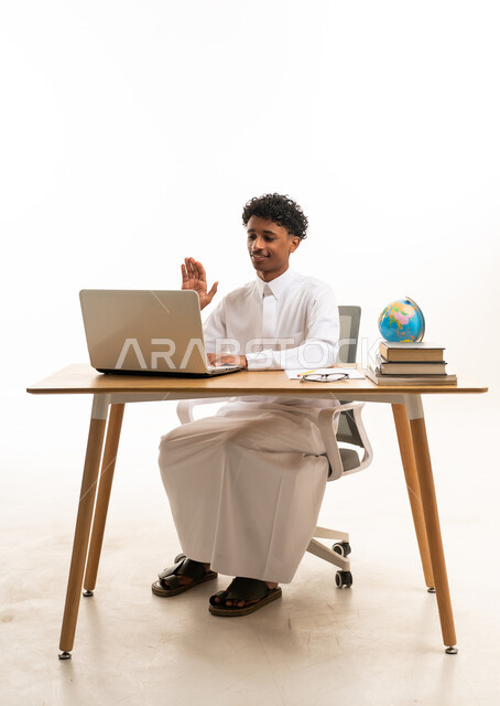 رجل سعودي بالثوب التقليدي يستخدم الكمبيوتر المحمول