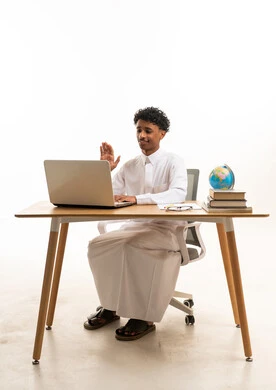 رجل سعودي بالثوب التقليدي يستخدم الكمبيوتر المحمول