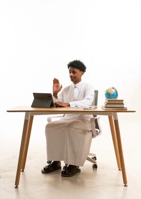 Saudi Man in Thobe Using Tablet at Office Desk