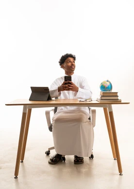 Saudi Man at Desk with Smartphone and Globe