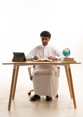 Saudi Male Student Studying at Wooden Desk with Book