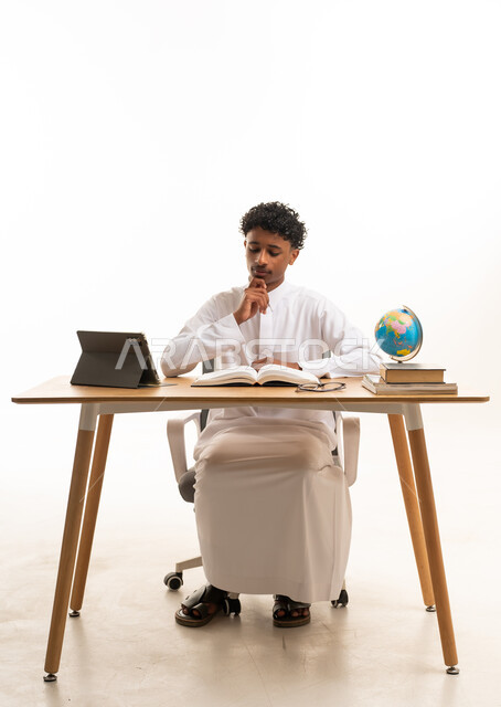 طالب سعودي بالثوب التقليدي يدرس على المكتب