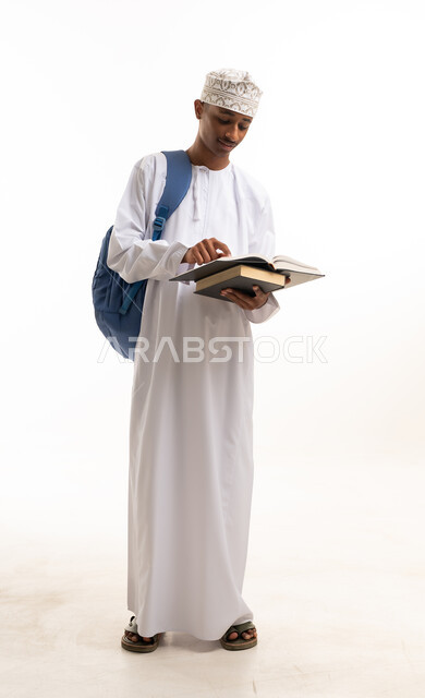 طالب عماني بالزي التقليدي يقرأ كتاباً