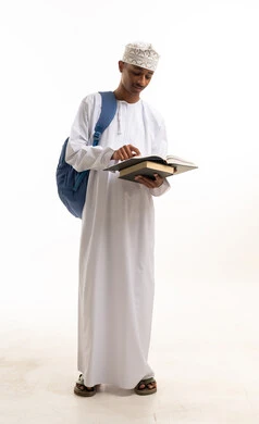 طالب عماني بالزي التقليدي يقرأ كتاباً