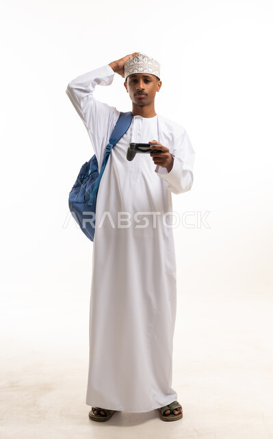 رجل عماني يحمل جهاز تحكم ألعاب بخلفية بيضاء
