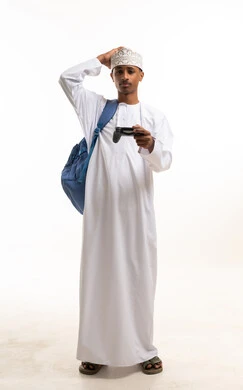 رجل عماني يحمل جهاز تحكم ألعاب بخلفية بيضاء