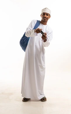 طالب عماني يحمل جهاز تحكم ألعاب وحقيبة ظهر