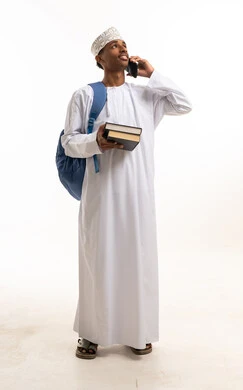 طالب عماني يحمل كتباً ويتحدث بالهاتف خلفية بيضاء