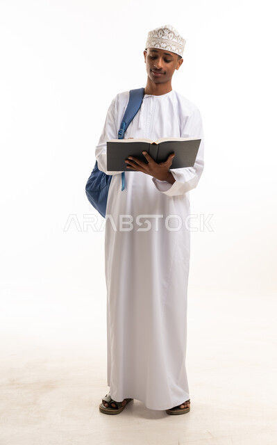 Young Omani Student in Traditional Dress Reading a Book
