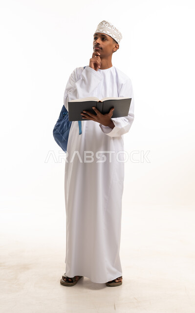 طالب عماني يفكر مع كتاب مفتوح بخلفية بيضاء