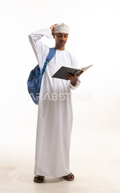 طالب عماني يحمل كتاباً وحقيبة ظهر بخلفية بيضاء
