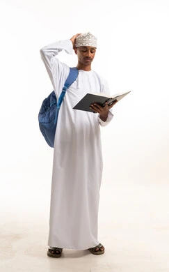 طالب عماني يحمل كتاباً وحقيبة ظهر بخلفية بيضاء