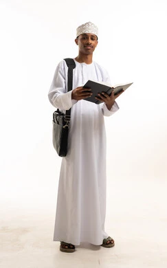 طالب عماني يقرأ كتاب بالزي التقليدي