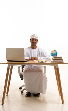رجل عماني جالس على مكتب مع حاسوب محمول