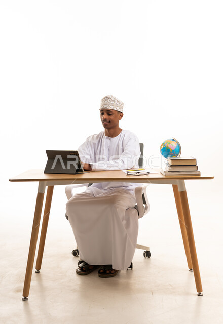 رجل عماني يعمل على جهاز لوحي في مكتب