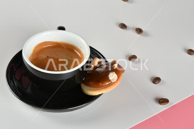 صورة مقربة لفنجان القهوة برغوة مع قطعة حلوى لذيذة وحبوب البن ، مشروب الكابتشينو الساخن ، قهوة اسبريسو ، مشروبات ساخنة لذيذة ، فنجان القهوة الساخن ، خلفية ملونة