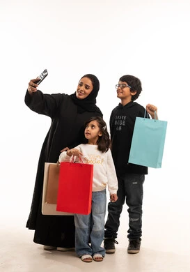 أم سعودية مع أطفالها وحقائب التسوق سيلفي