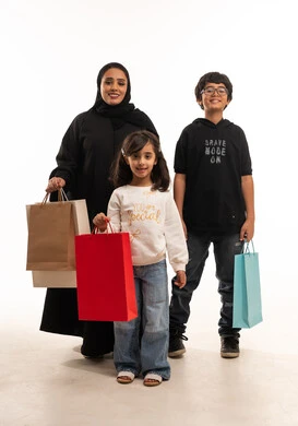 أم سعودية وأطفالها مع حقائب تسوق ملونة