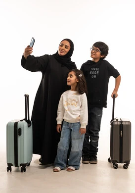 أم سعودية مع أطفالها وحقائب السفر يلتقطون سيلفي