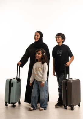 أم إماراتية وأطفالها مع حقائب سفر بخلفية بيضاء
