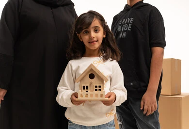 Saudi Girl Holding House Model with Family and Boxes