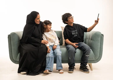 Saudi Mother and Children Taking Selfie on Sofa in Studio