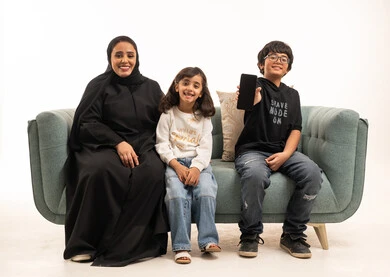 عائلة سعودية مع هاتف ذكي على أريكة خضراء