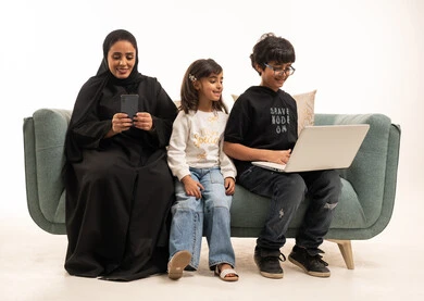 أم سعودية وأطفالها مع كمبيوتر محمول وهاتف ذكي