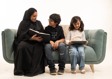Saudi Mother Reading Book with Children on Green Sofa