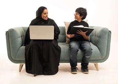 Saudi Mother and Son Studying with Laptop Indoors