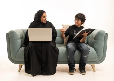 امرأة سعودية مع كمبيوتر محمول وطفل يقرأ كتاب