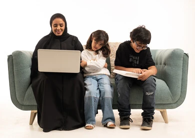 أم سعودية تعمل على الحاسوب مع أطفالها