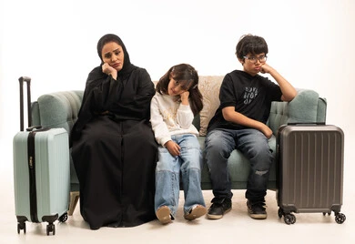 عائلة سعودية مع حقائب سفر ينتظرون على الأريكة