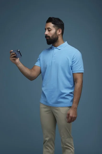 Saudi Man Using Smartphone in Blue Polo Shirt Studio