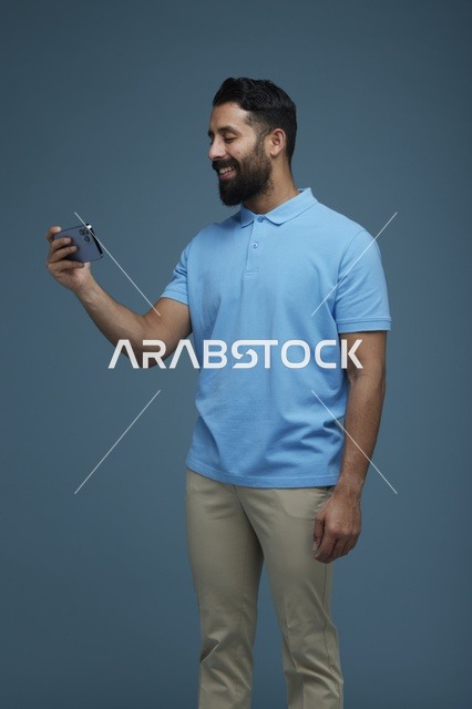 شاب سعودي يستخدم الهاتف بقميص بولو أزرق