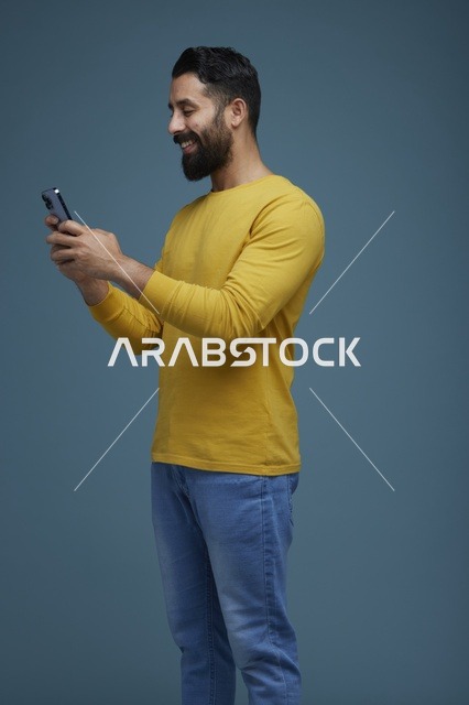 شاب سعودي يستخدم الهاتف الذكي بملابس كاجوال