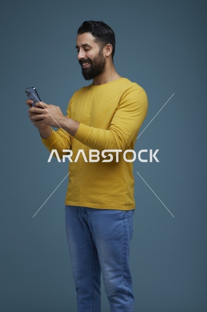شاب سعودي يستخدم الهاتف الذكي بملابس كاجوال