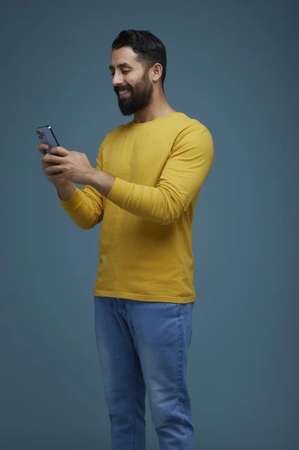 شاب سعودي يستخدم الهاتف الذكي بملابس كاجوال