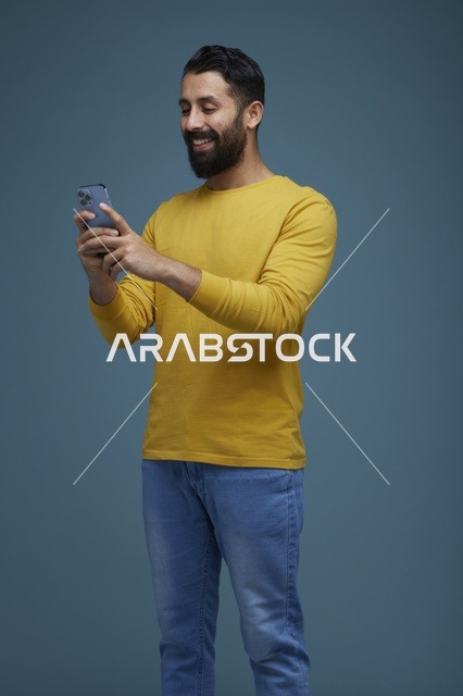 Saudi Man Using Smartphone on Blue Background