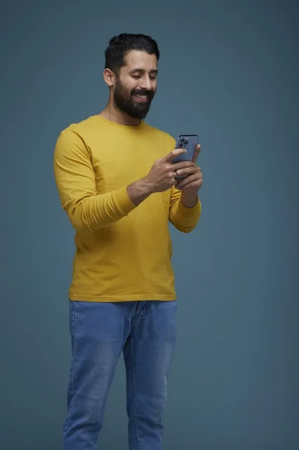 Saudi Man Using Smartphone in Casual Yellow Shirt
