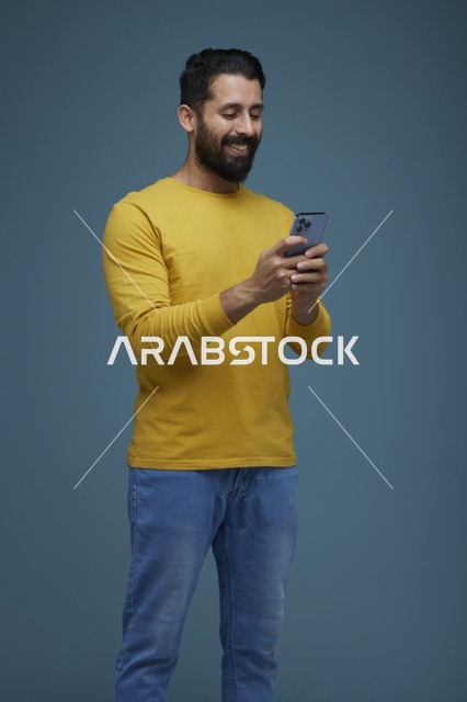 Saudi Man Using Smartphone in Casual Yellow Shirt Studio