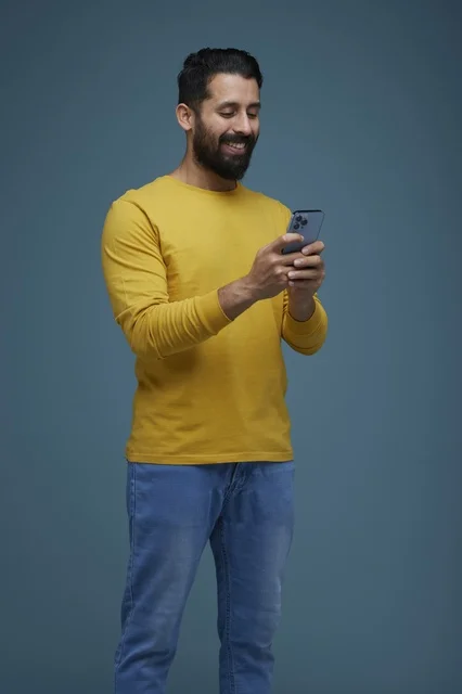 Saudi Man Using Smartphone in Casual Yellow Shirt Studio