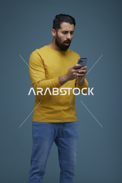 شاب سعودي مصدوم يستخدم الهاتف الذكي بخلفية زرقاء