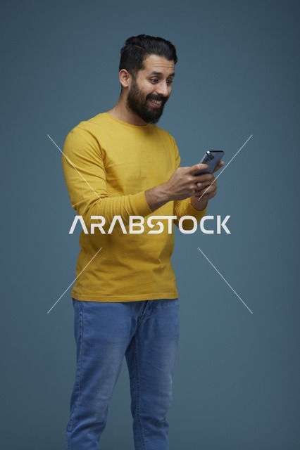 شاب سعودي يستخدم الهاتف الذكي بملابس كاجوال صفراء