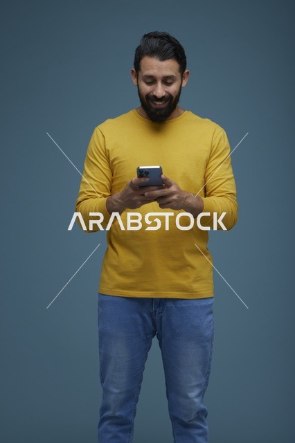 شاب سعودي يستخدم الهاتف الذكي بملابس كاجوال صفراء