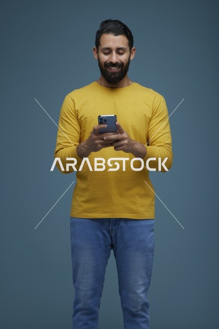 شاب سعودي يستخدم الهاتف الذكي بملابس كاجوال