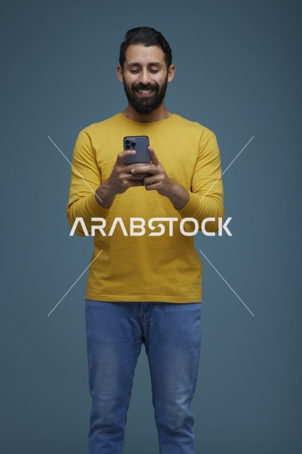 شاب سعودي يستخدم الهاتف الذكي بملابس كاجوال صفراء